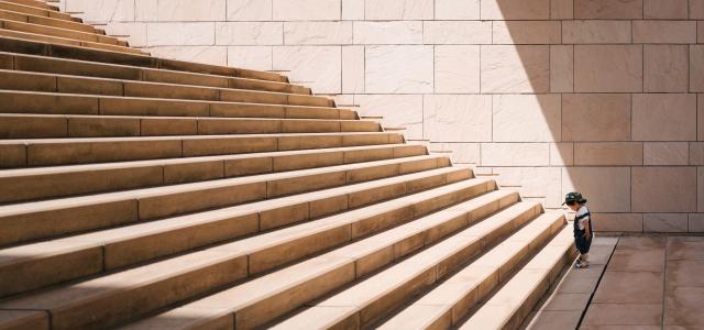 Toddler standing at the bottom of a stone staircase